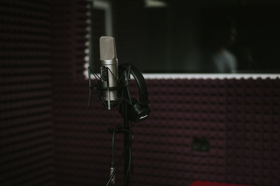 A professional condenser microphone glowing in a purple-lit cam studio