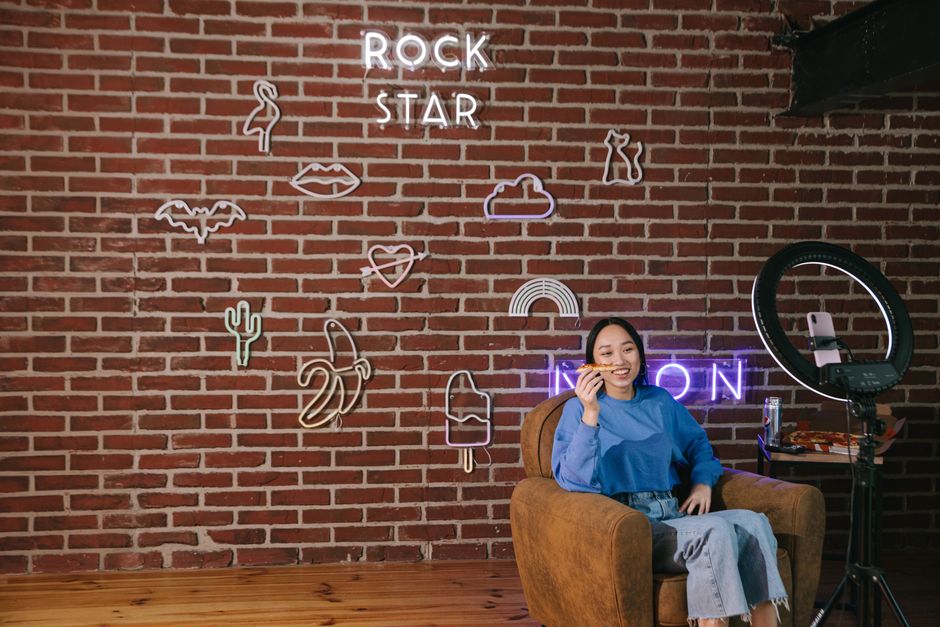 Performer filming TikTok content with ring light in neon-lit studio