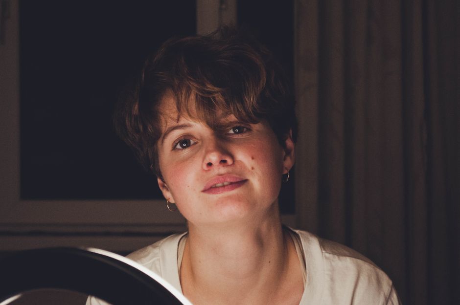 A cam performer smiling authentically at their webcam in a warmly lit home studio